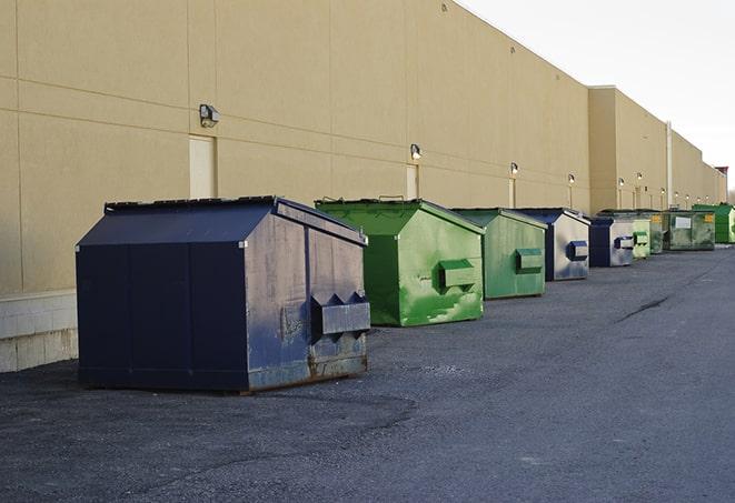 a compact construction dumpster being emptied by a waste disposal truck in Anniston, AL